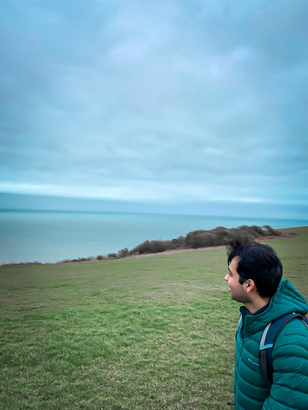 Utkarsh hiking across the seven sisters cliffs in the UK. Utkarsh is looking out at the ocean.